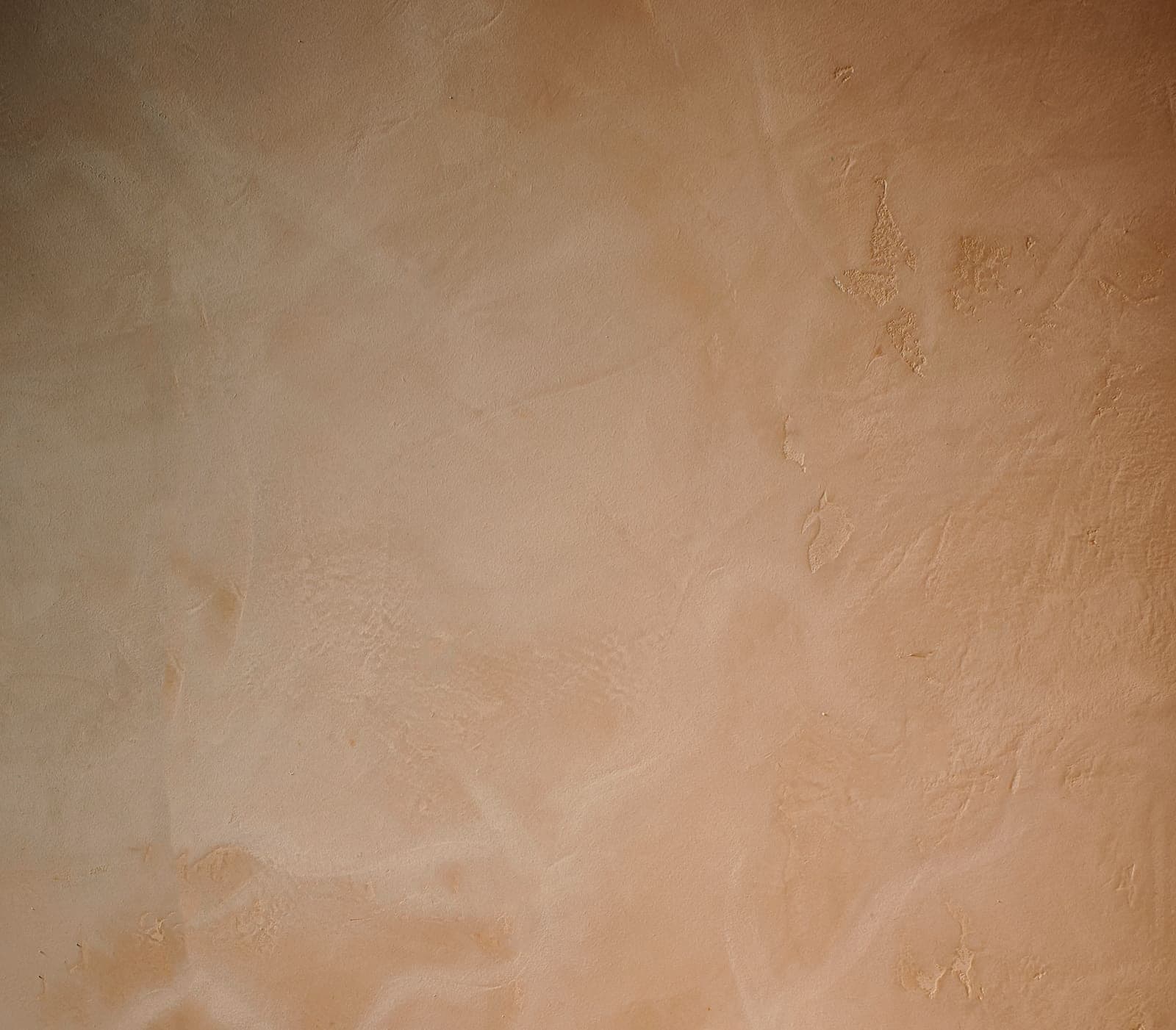 A close view of a hand-troweled ochre lime-plaster wall.